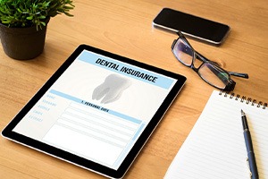 Dental insurance form on tablet next to notepad
