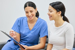 Dental assistant showing patient forms on clipboard