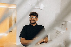 Patient with black glasses smiling in treatment chair