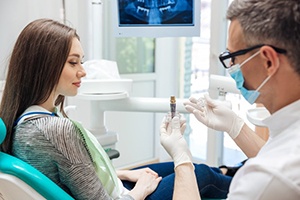 Dentist showing a patient a dental implant model