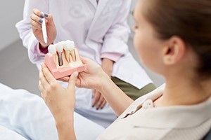 Dentist pointing a dental implant model to explain osseointegration to patient