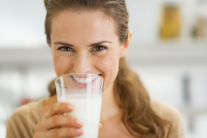 Woman smiling while drinking a glass of milk
